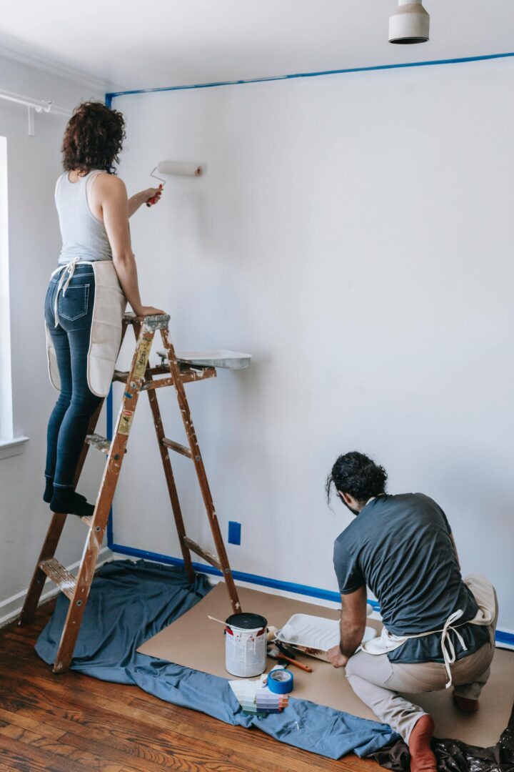 Un couple peignant un mur au rouleau pour rénover leur maison eux-même