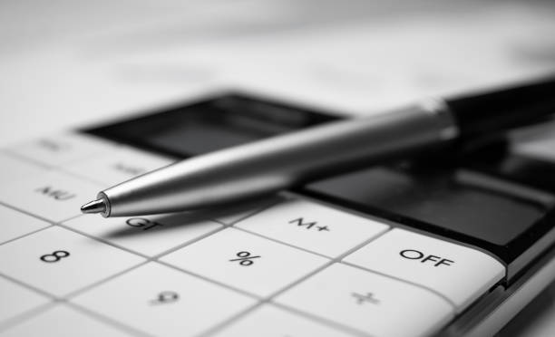 Stylo en argent posé sur une calculatrice blanche