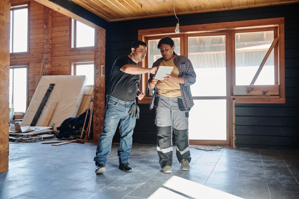 Ouvrier et architecte étudiant un plan de travaux de rénovation d'une maison