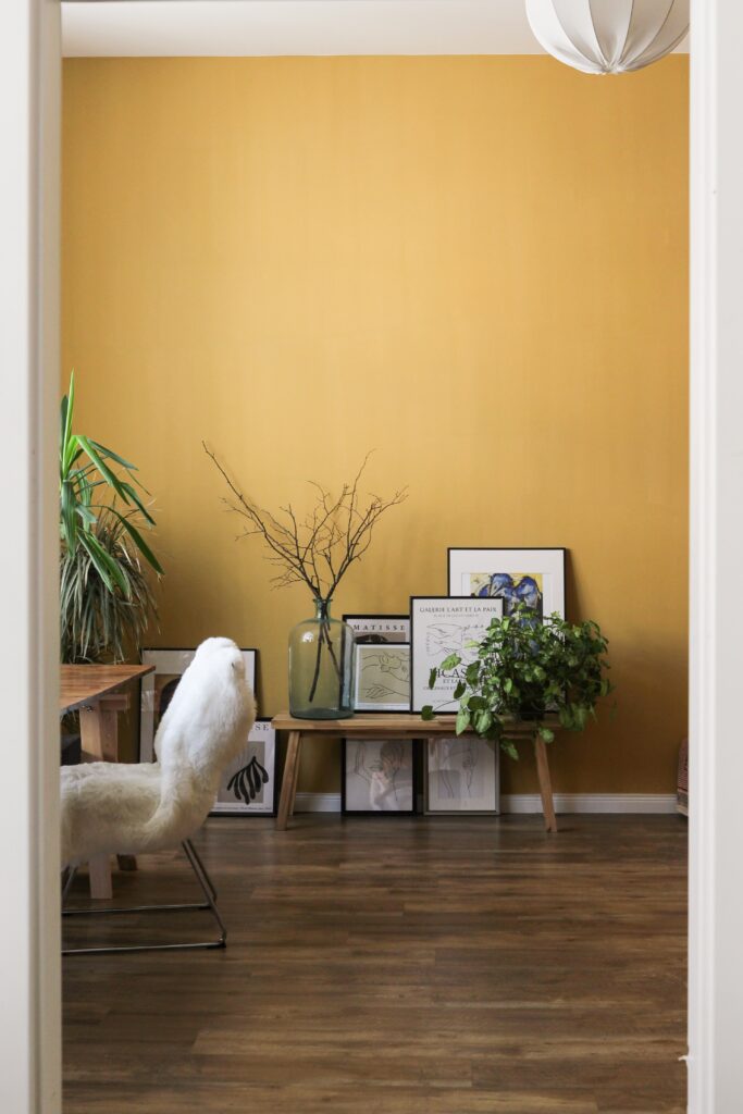 Mur jaune dans un appartement avec cadres et plantes au sol