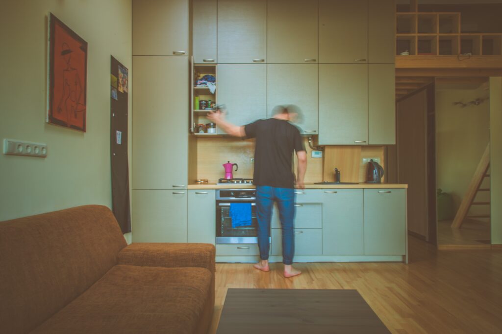 Homme se servant dans la cuisine d'un petit appartement