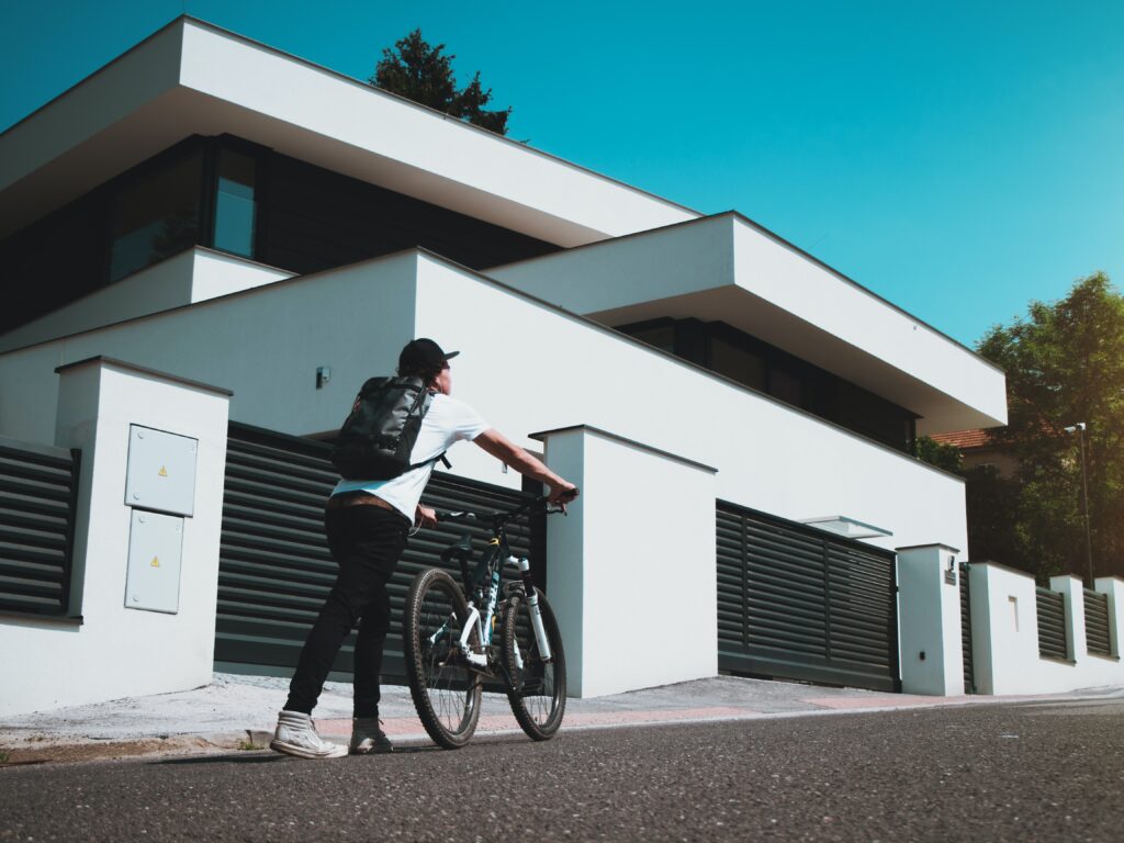 Homme en vélo devant une maison moderne