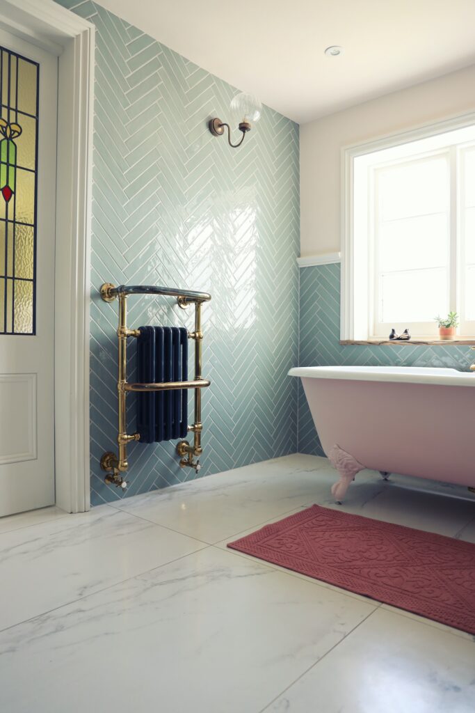 une salle de bain rénovée avec des petits carreaux de carrelage vert amande aux murs et de grandes dalles de carrelage à effet marbre blanc au sol