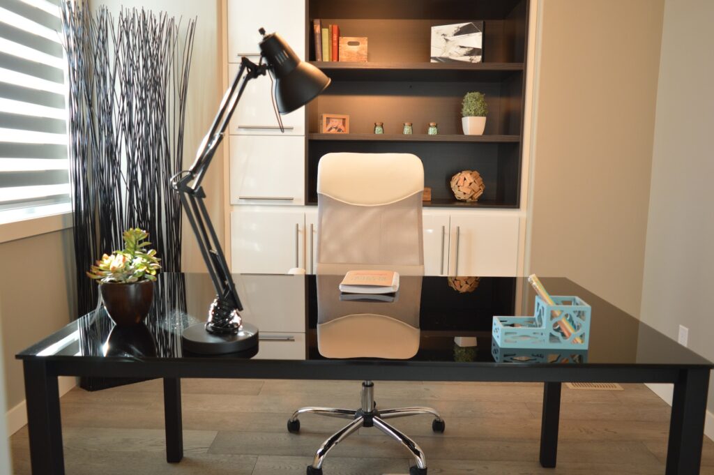 un espace bureau à la maison très moderne, avec chaise ergonomique, grande lampe, bureau en verre et métal, et une bibliothèque en bois sombre