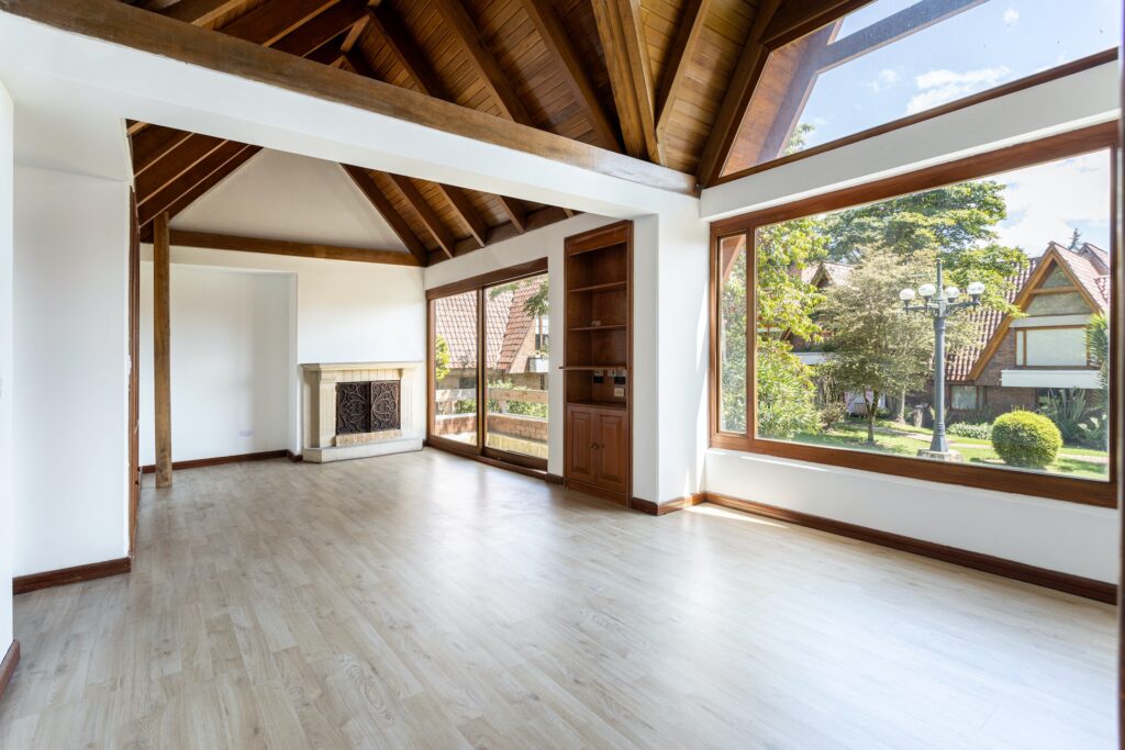 intérieur maison moderne architecte avec parquet, murs blancs, toiture en bois à poutres exposées, et grandes verrières