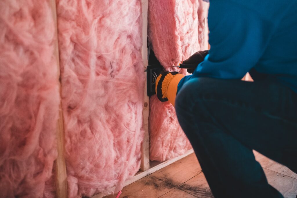 un ouvrier pose une laine de verre rose pour l’isolation d’un plafond en appartement