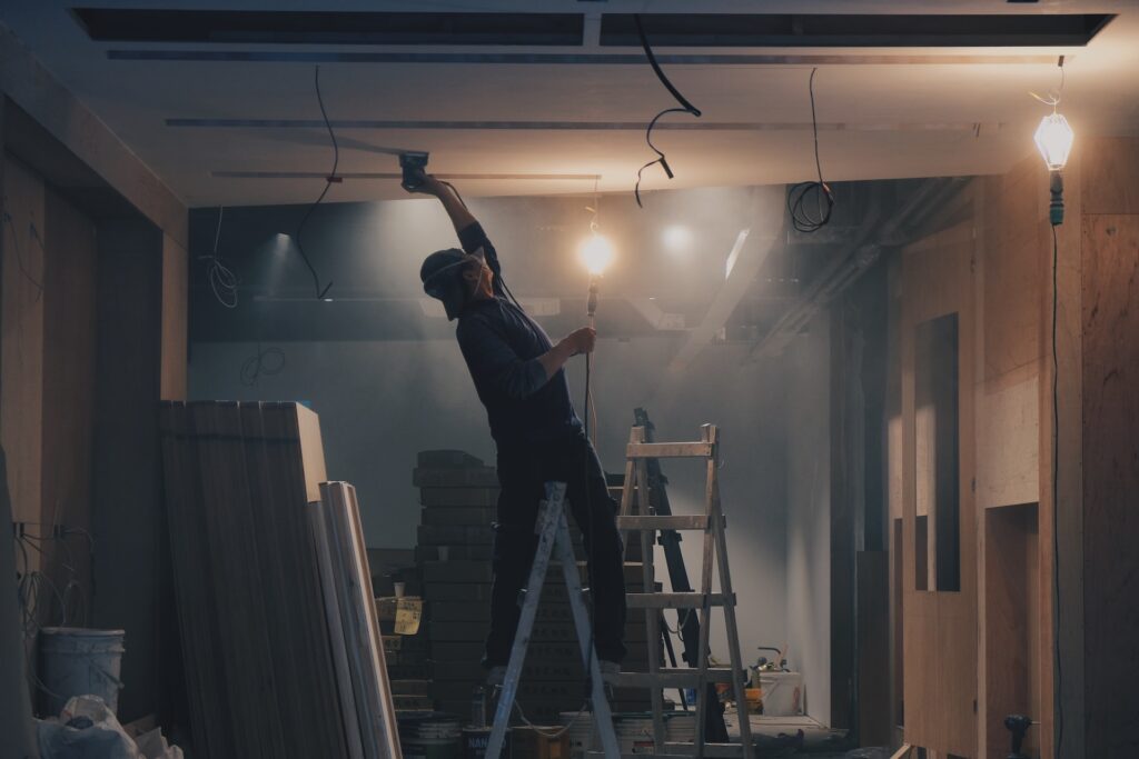 exemple d’une pose d’isolation plafond en appartement de type plafond tendu, avec un ouvrier qui pose le plafond tendu à l’aide d’une spatule métallique