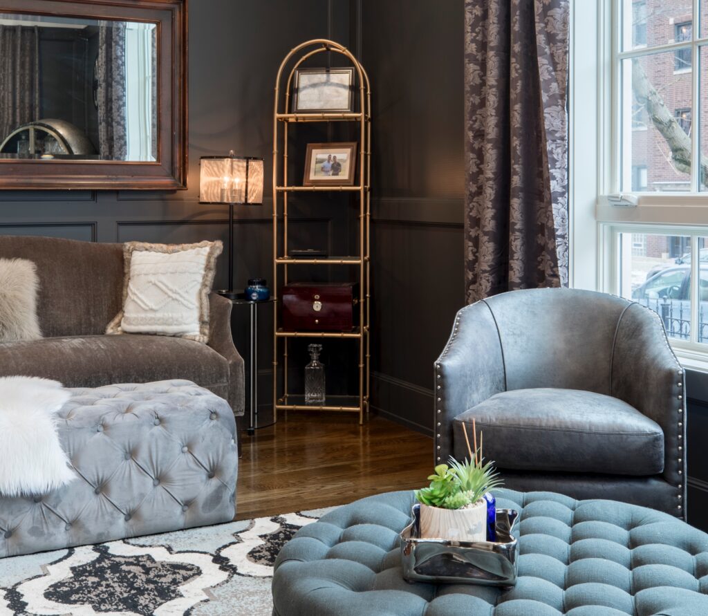 Un salon très illuminé comportant un fauteuil, un canapé et un pouf, dans les rons bleu-gris.
