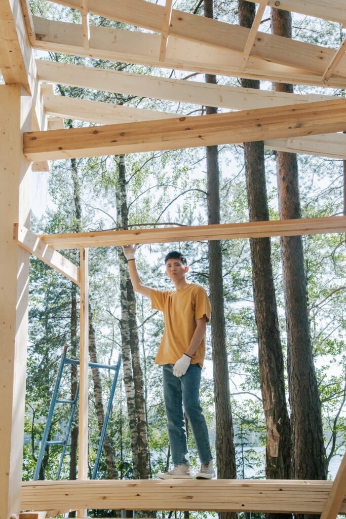 Jeune homme sur un échafaudage de maison en bois, dans une forêt