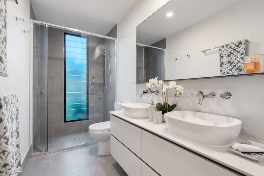 exemple de rénovation de salle de bain en appartement avec un lavabo double vasque en céramique blanche