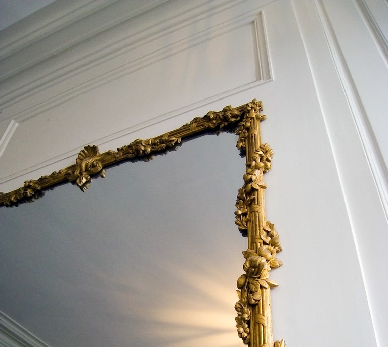 miroir à moulures dorée sur mur blanc dans appartement haussmannien