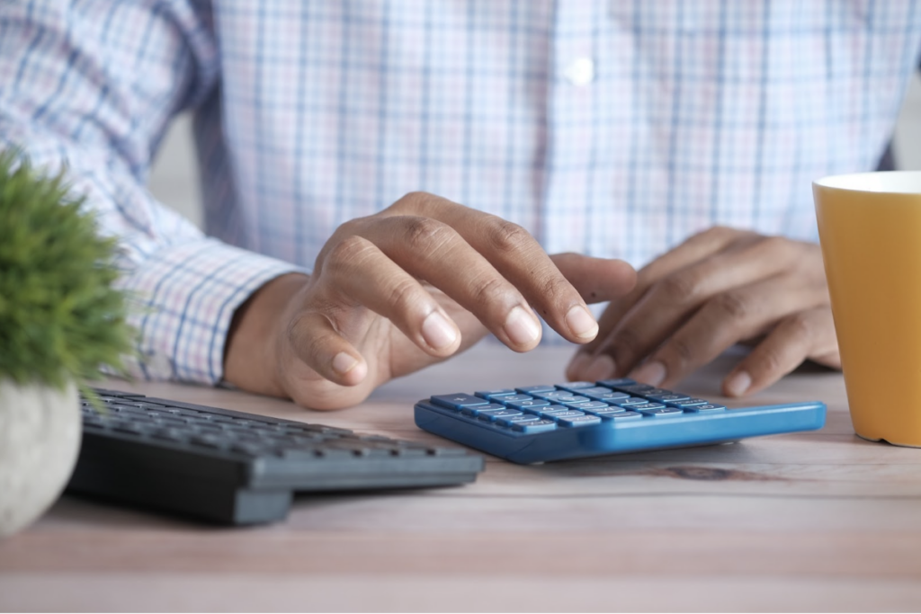 Un homme tape sur une calculatrice, il est visiblement en train de faire des comptes.