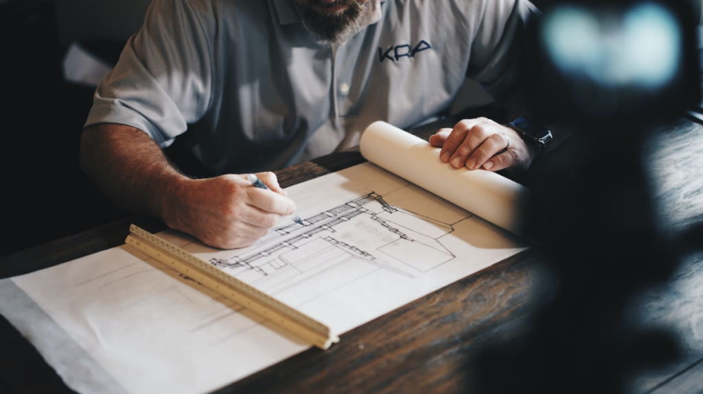 Un homme est en train d'écrire sur un calepin. il dessine avec précision une structure architecturale