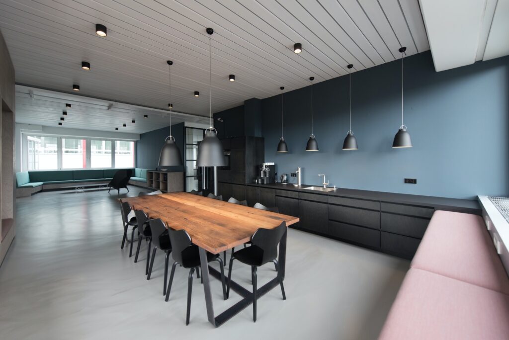 Une cuisine avec une table à manger. Le mur est bleu et la pièce est grande.