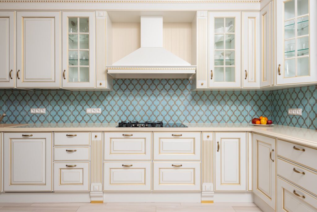 cuisine avec placards avec moulures soulignées par de la peinture or, crédence entre les placards hauts et bas à motifs bleus