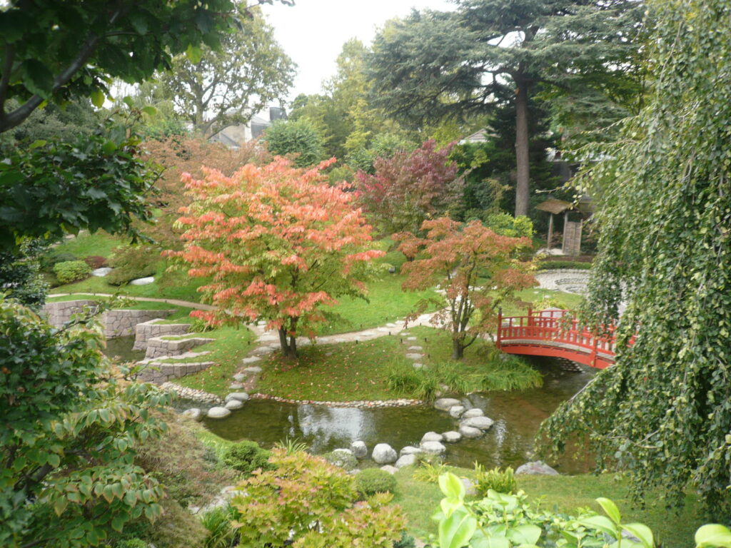 Jardin moderne fleuri avec un pont japonais.