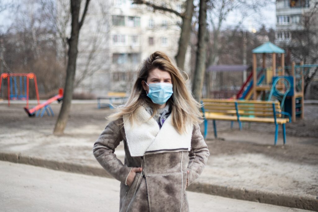 Jeune femme portant un masque couvrant son nez et bouche. Elle marche dans la rue en hiver