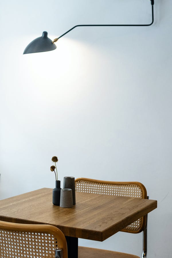 petite table avec deux chaises surplombée d'une lampe allumée