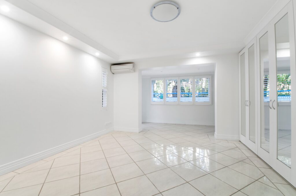 Grande salle vide, neuve et complètement blanche d'une luminosité éclatante avec une pose de carrelage au sol