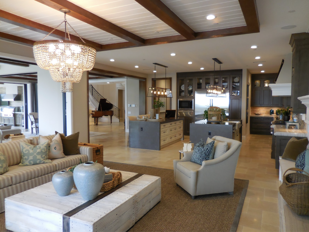 Grand salon moderne et coloré qui ouvre sur d'autres pièces en arrière-plan. L'intérieur est décoré et composé de nombreux meubles luxueux et avec des matériaux haut-de-gamme