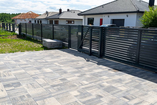 une clôture en panneaux moderne de couleur anthracite, un portail électrique visible vers le garage et un guichet avec une boîte aux lettres. 