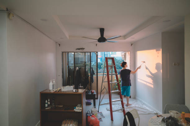 Homme peignant la finition d'une plaque de placo dans un salon